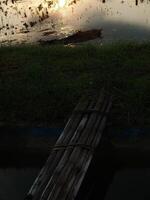 relaxant et calmant paysage de un vieux bambou pont traversée un irrigation Chanel à riz champ avec d'or Jaune lumière de le Soleil monter photo