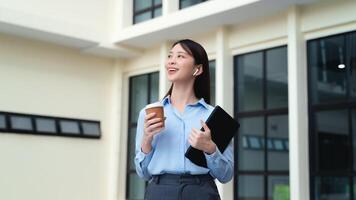 une affaires femme est permanent dans le ville avec une tasse de café et une tablette photo