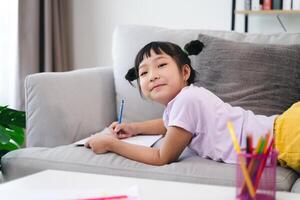 une Jeune fille est séance sur une canapé avec une crayon et une carnet photo