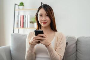 une femme est séance sur une canapé et en portant une cellule téléphone photo