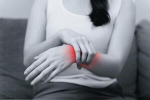 fermer de femme séance sur canapé détient sa poignet, main blessure avec rouge surligner photo