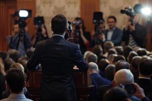 Masculin orateur à podium orienté vers une foule de journalistes et appareils photo