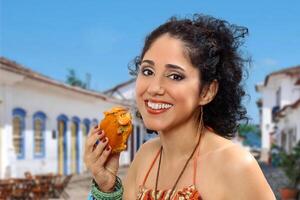 souriant brunette modèle avec sa acaraje, une brésilien collation, dans sa mains photo