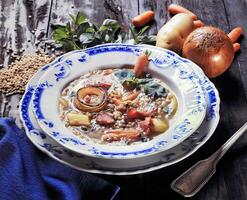 blé soupe avec patates, oignons, Bacon et carottes sur assiette photo