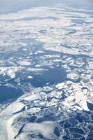 vue aérienne de la fenêtre de l'avion au-dessus des nuages jusqu'à la mer gelée couverte de neige, air frais d'hiver glacial photo