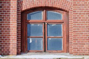 une fenêtre en verre arquée sur le vieux mur de briques rouges photo