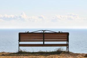 banc vide sur la falaise avant le fond de la mer, endroit paisible et calme pour penser seul photo