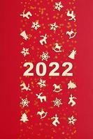 bonne année 2022 numéros sur fond rouge avec des étoiles dorées et des décorations en bois de cristmas photo