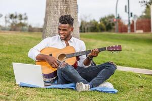 homme séance sur herbe en jouant guitare photo