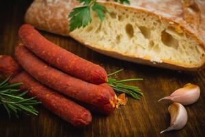 fumé saucisses avec pepperoni, ail, poivre, pain et Romarin sur une vieux en bois tableau. de face voir. photo