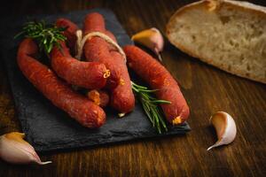 fumé saucisses avec pepperoni, ail, poivre, pain et Romarin sur une vieux en bois tableau. de face voir. photo