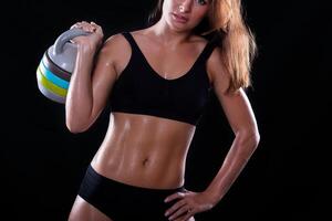 aptitude fille avec kettlebell sur une foncé Contexte photo