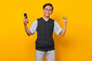 portrait d'un bel homme asiatique joyeux tenant un smartphone et se réjouissant de célébrer la chance photo