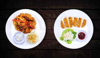 côté plats, poulet sucré plat et poulet épicé sur blanc assiette sur foncé en bois arrière-plan, Haut voir. photo