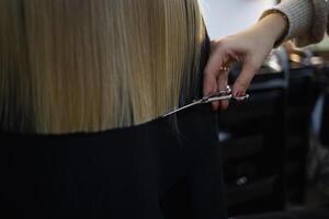 le coiffeur dans le salon de coiffure coupes le cheveux de une peu mignonne fille photo