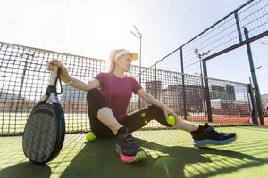 content femelle pagayer tennis joueur pendant entraine toi sur Extérieur tribunal à la recherche à caméra. copie espace. photo