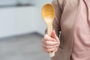 en bois cuillère dans main isoler photo