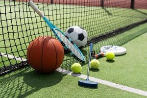 une variété de des sports équipement comprenant un américain football, une football balle, une tennis raquette, une tennis balle, et une basketball photo