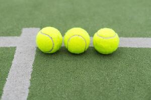 Jaune des balles sur herbe gazon près padel tennis raquette derrière net dans vert tribunal en plein air avec Naturel éclairage. pagayer est une raquette jeu. professionnel sport concept avec copie espace. photo