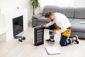 Jeune homme en changeant - fixation une sale air purificateur hepa filtre après en utilisant pour une longue temps. une dépanneur remplacer et installation le air purificateur filtre. soins de santé et bien-être photo