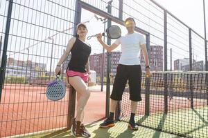 des sports couple avec padel raquettes posant sur tennis tribunal photo