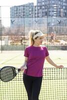 actif Jeune femme en essayant à battre le Balle par padel raquette tandis que en jouant tennis dans le tribunal photo