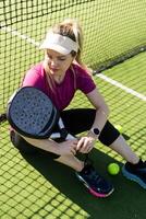 actif Jeune femme en essayant à battre le Balle par padel raquette tandis que en jouant tennis dans le tribunal photo