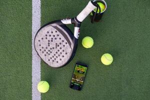 une tennis balle, une raquette et une mobile téléphone avec une mettre écran mensonge sur une bleu Contexte. le concept de La publicité une tennis club ou commande prestations de service. horizontal photo