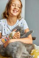 adolescent fille avec une cassé bras orthopédique jeter jouer avec chat photo