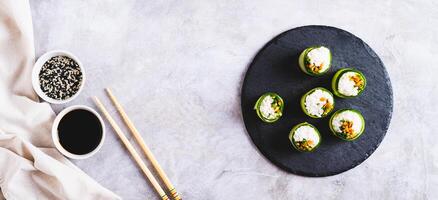 végétarien Sushi riz, carottes et vert oignons enveloppé dans concombre Haut vue la toile bannière photo