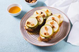 pièces de poire, ricotta, mon chéri et des noisettes sur seigle bruschettas sur une assiette sur le table photo