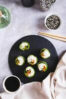 végétarien Sushi riz, carottes et vert oignons enveloppé dans concombre Haut et verticale vue photo