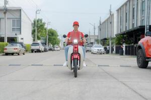 livraison cavalier sur rouge moto avec isolé nourriture boîte garé en plein air photo