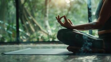 une femme est assis sur une yoga tapis par une fenêtre, entouré par les plantes et bois photo