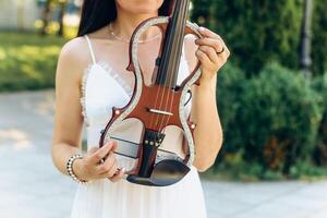 une fragment de un électrique violon, une violon dans le mains de une les musiciens fille photo