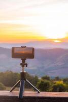 une téléphone intelligent est enregistrement le Soleil réglage plus de une Montagne gamme. photo