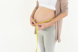 Enceinte femme en utilisant mesure ruban à vérifier Taille de ventre grossesse et bébé développement photo