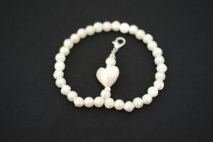 Collier de blanc perles et une cœur sur une noir Contexte photo