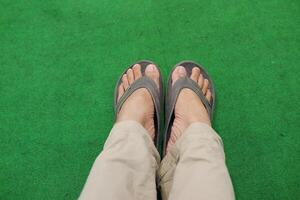 Masculin pieds dans des sandales sur une vert tapis. fermer. photo