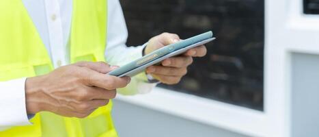 inspecteur ou ingénieur est inspecter construction et qualité assurance Nouveau maison en utilisant une tablette. ingénieurs ou architectes ou contacteur travail à construire le maison avant remise il plus de à le propriétaire photo