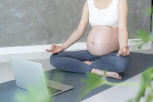 Enceinte femme Faire yoga sur exercice tapis. méditer pour à court terme accouchement de méditer attrayant Enceinte femelle des loisirs et se détendre, respiration et calme avec yoga. soi se soucier photo