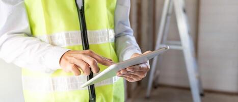 inspecteur ou ingénieur est inspecter construction et qualité assurance Nouveau maison en utilisant une tablette. ingénieurs ou architectes ou contacteur travail à construire le maison avant remise il plus de à le propriétaire photo