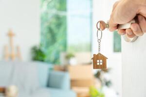 déménagement, déménagement. la clé a été insérée dans la porte de la nouvelle maison, à l'intérieur de la pièce se trouvait une boîte en carton contenant des effets personnels et des meubles. emménager dans l'appartement ou la copropriété photo