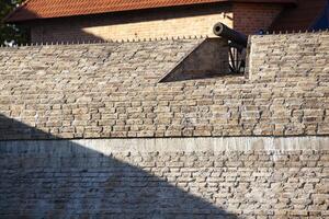 un ancien brique mur de le forteresse. une grand acier canon sur Haut de le mur. Contexte. texture. horizontal. photo