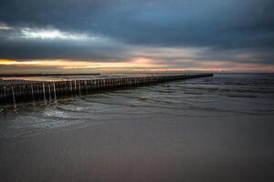 le coucher du soleil sur plage avec une en bois digue dans leba, baltique mer, Pologne photo