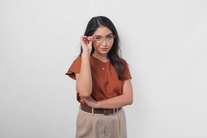 élégant asiatique femme dans marron chemise portant lunettes Faire une élégant et élégant pose isolé par blanc Contexte. photo