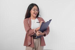 Jeune asiatique affaires femme dans lunettes en portant une document et stylo à écrire rapport, isolé par blanc Contexte. photo