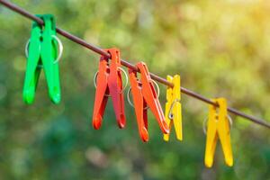 coloré pinces à linge sur une corde sur une Contexte de vert des arbres dans bokeh photo