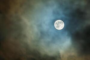 le plein lune dans le nuit ciel par le des nuages photo