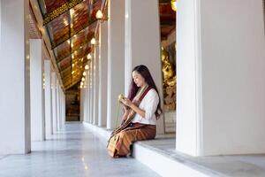 bouddhiste asiatique femme dans traditionnel tissu est pliant lotus feuille dans bouddhiste temple comme méditation processus pour paix et tranquille religion entraine toi concept photo